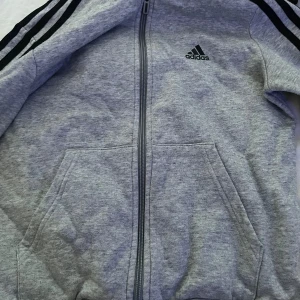Grå adidas tjocktröja - En grå adidas tjocktröja ( zip)med svarta ränder