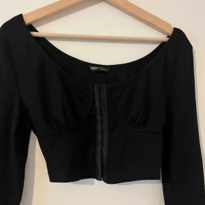 Svart topp - Svart croptop med snygga detaljer. Aldrig använd. Storlek L
