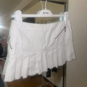 Vit kjol med dragkedjor och volanger - En vit jeanskjol med volanger nedtill i storlek 36 (midjemått 37), köpt i Frankrike
