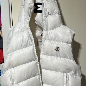 Moncler väst - Västen är i Storlek 2 (M)  Den är enkel,fin och västen är helt ny. Den är äkta och har äktighets bevis. 
