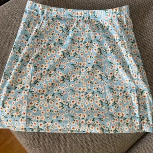 Blommig kjol - Säljer en blå blommig kort kjol med en liten slits. Storlek XS men passar som S oxå.  Använd några gånger förra sommaren men i ett jätte fint skick. 