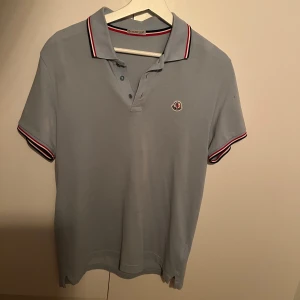 Moncler Piké - Babyblå moncler Piké, pyttelitet hål på vånstra axeln. 