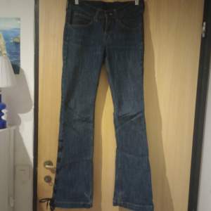 mörblåa lågmidjade bootcut jeans med knytdetalj på högra benet