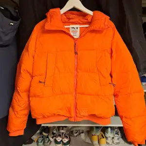 Orange dunjacka från märket Kari Traa. I jackan står det storlek L men vet inte riktigt hur den passar.