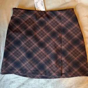 Rutig minikjol - Skitsnygg stretchig kjol. Prislappen kvar. Storlek XS. Liten slits en sidan.