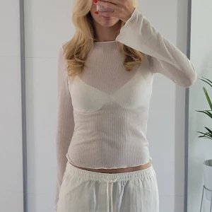 Vit genomskinlig topp - Vit ribbad topp från H&M med trumpetärmar. Genomskinlig och snygg med en fin bh under.   Hör av dig om du har frågor!