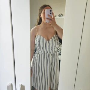 Vit sommarklänning - En vit, randig sommarklänning med smala axelband och har ett tillhörande tygskärp som kan användas hur man vill🤍 PERFEKT att ha till ex. skolavslutning, student eller midsommar