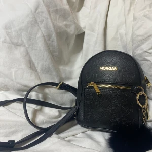 Svart Läder Morgan Ryggsäck  - En vintage Morgan väska med fjäril print, gjort med äkta läder och har justerbara axelband.