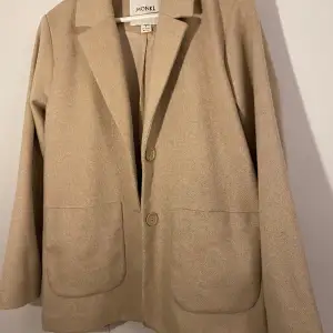 Beige kavaj i ett kraftigare material. Rak i modellen. Passar S/M. Sparsamt använd, som ny