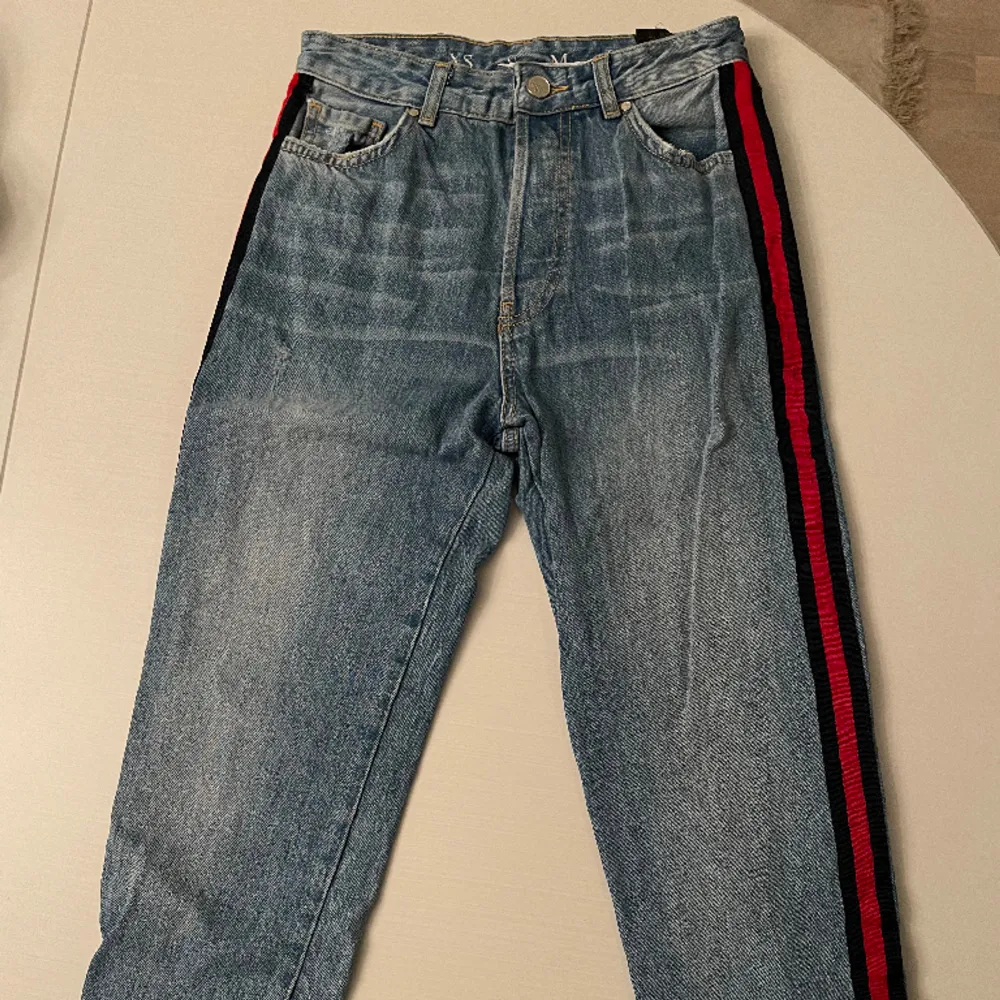 Blå jeans (lite ljusare i verkligheten) med röd rand på sidan av benen och lite slitningar. Från bikbok, i bra skick! . Jeans & Byxor.