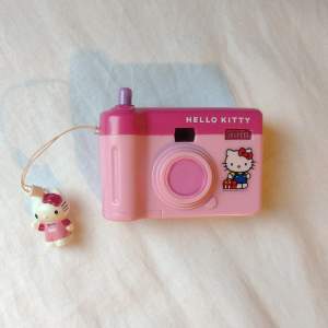 Leksakskamera med Hello Kitty. Trycker man på knappen så kommer nya bilder på henne upp i titthålet (bild 3). Finns även en lucka under så man kan lägga i smågrejer ☺️ FINNS KVAR