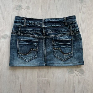 Lågmidjad mörkblå jeanskjol  - Mörkblå lågmidjad jeanskjol från Sublevel i storlek S som jag har sytt upp från en längre kjol. Tvärs över midjan är det ca 38 cm + stretch och längs med sidan är det ca 30 cm. Fint skick. Använd gärna köp nu!