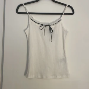 Linne med rosett och spets - Ett Linne från H&M med vit spets och svart rosett på framsidan. Prislappen hänger kvar på och linnet är aldrig använt.   Säljer då jag aldrig använt🤍