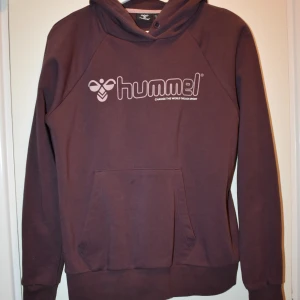 Hoodie Hummel - Armhåla till armhåla = 52.5cm Armhåla till handled = 51.5cm Axel till handled = 62.5cm Axel till axel = 45.5cm Nacke till midja = 60.5cm  Knappt använd Färg: Burgundy Material: Bomull och Polyester Märke: Hummel