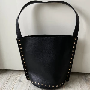 Läderväska med studs - Cool väska i fejkläder med guldiga studs 🔥 I väldigt fint skick! Får plats med skolböcker och ev. en liten laptop 🖤