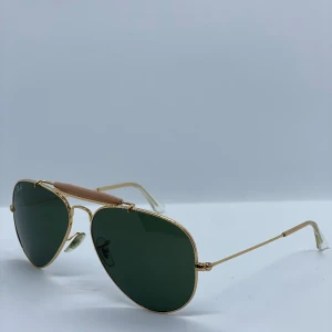 Ray-Ban Solglasögonen, 58mm - Hej! Jag säljer denna solglasögon av det kända märket Ray-Ban! Då den är sparsamt använd. Den är i ny skick. Den har guldig stål med gröna glass. 58mm. Går att skicka den via posten, annars avhämtning i Västerås.