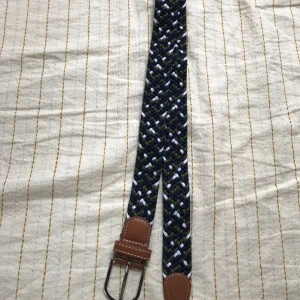 Flätat bälte - Flätat bälte i nyskick! Med färgerna vit, mörkgrön och mörkblå. Hör av er vid funderingar.