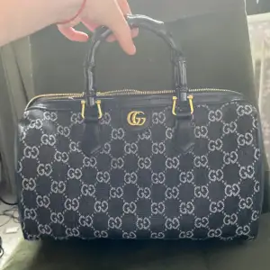 En Gucci dupe, En mörkblå,grå, guld och svart väska som ser ganska liten ut men har jätte mycket plats. Säljer då det inte är min stil. Är som en liten weekend bag.