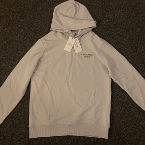 Stone Grey Calvin Klein hoodie - Helt oanvänd Calvin Klein hoodie i storlek 170 Säljer eftersom den inte passar mig. Hör av er vid funderingar