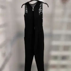 Jättefin svart jumpsuit som är vadderad och kortärmad! Den har spets över ryggen vilket är jättesnyggt! Den har dessutom fickor vilket är en dröm!! Storlek L