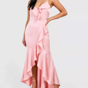 Rosa balklänning med volanger - Nyskick, aldrig använd. Köpt från boohoo - nypris 810kr. Säljer denna satinklänning för att midjan var för stor för mig, men den passade bra i längden (jag är 168, som jämförelse). Axelbanden är justerbara! Kontakta gärna privat om funderingar. PRIS KAN DISKUTERAS! Men va snabb för den finns inte att köpa på hemsidan längre. 