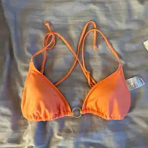 Bikiniöverdel i korall/peach-färg. Aldrig använd. Liten trots storlek 44 och knytningen gör den anpassningsbar.
