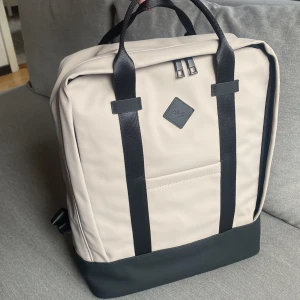 Ryggsäck  - Ryggsäck från Rizzo i vattenavvisande material.  Beige-grå i färgen.  Aldrig använd.  Mått:  Höjd 35cm Bredd 30cm Djup 13cm Ord.pris 499kr 