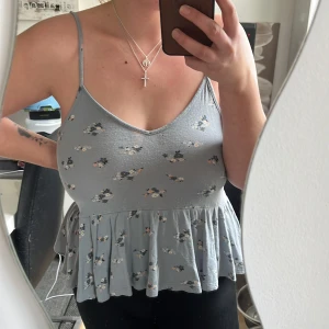 Topp - Blå topp med blommor, använd väl men i bra skick. Finns en fläck på framsidan samt ett litet hål, se bild två. 