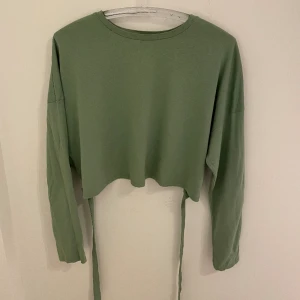 Grön topp med knytbar rosett  - Topp med knytbar rosett från bik bok. Använd fåtal gånger!