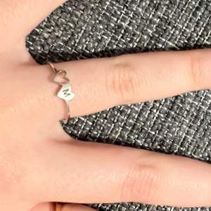 Väldigt fin, elegant ring i silverfärg. Den har två hjärtan som motiv, ett ”ihåligt” och ett med bokstaven M på!