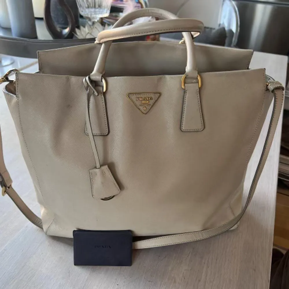 Prada Saffino leather cross body bag.  Vintage and well maintained with no signs of use on either the outside or inside interiors. Color: grey/ neutral beige/ Sand shell.   No smell and no direct signs of use. 100% authentic. Comes with dustbag.. Väskor.