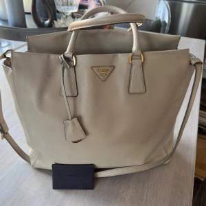 Prada Saffino leather cross body bag.  Vintage and well maintained with no signs of use on either the outside or inside interiors. Color: grey/ neutral beige/ Sand shell.   No smell and no direct signs of use. 100% authentic. Comes with dustbag.