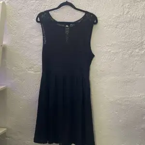 En svart klänning med mönster i storlek S. Den ser blå ut på bilden men är svart i verkligheten.