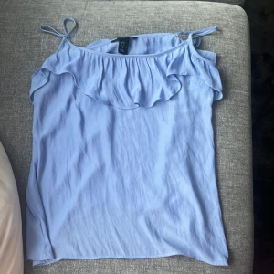 Blått linne med volang - Ljusblått linne med volang, använt två gånger så den är i super skick, dock har jag sytt upp banden då de är för långa men man kan bara sprätta upp det o få de långa igen