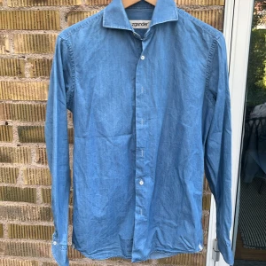 Skjorta - Säljer denna jeans skjorta från zegander som inte använd längre. Armarna är rundade längst ute vid knappen och alla knappar på skjortan är vita. Sparsamt använd