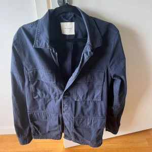 A days march Overshirt  - Snygg marinblå Overshirt i väldigt bra skick, Använd men inga fläckar eller defekter. Stl Small  Nypris 1500