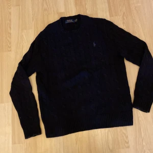 Ralph Lauren tröja - Begagnad mörkblå kabelstickafd Ralph Lauren tröja i fint skick. Storlek xs, herr.