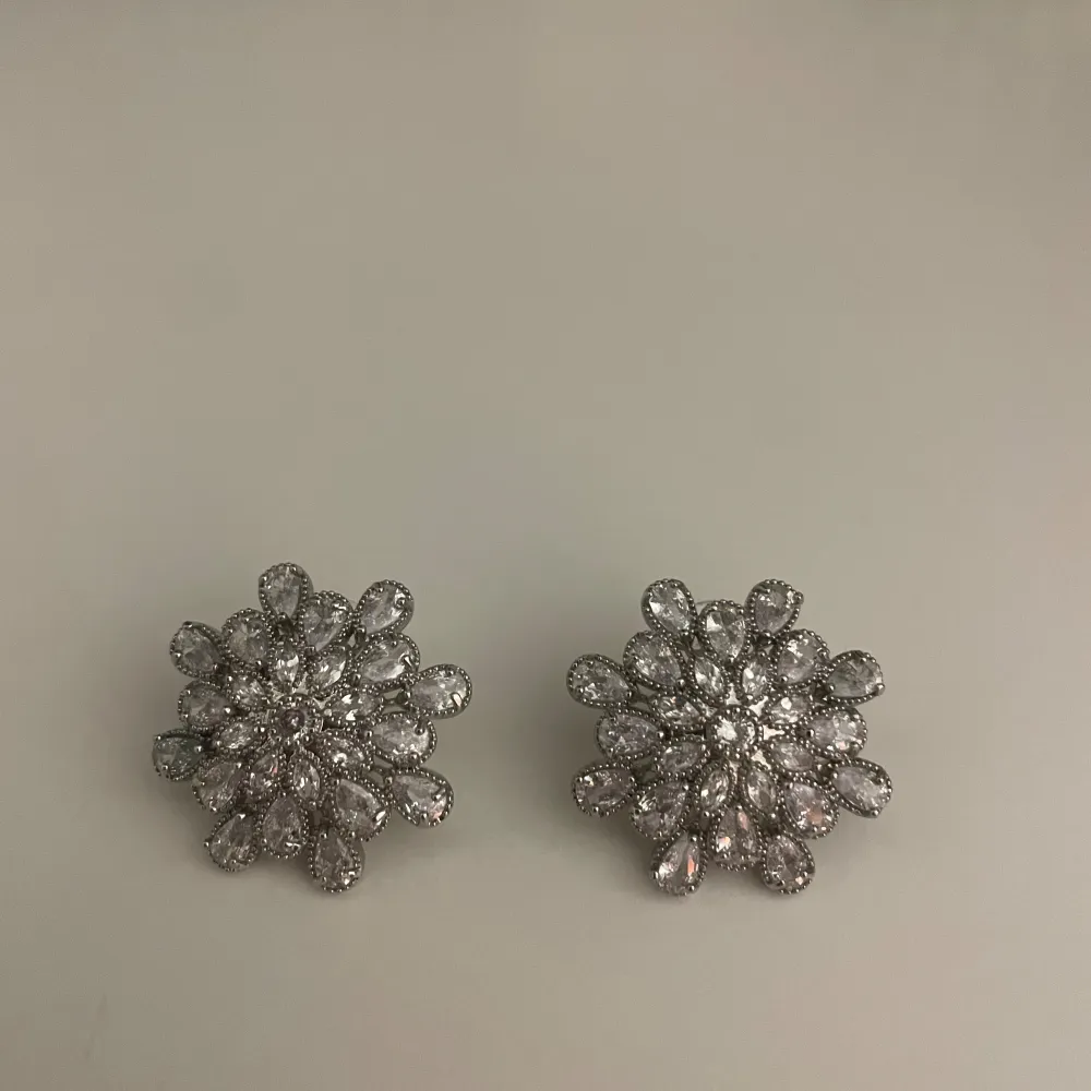 Dessa öronhängen är silvriga blommor med diamanter (fake diamanter).   För fler bilder skriv till mig på plick🩵.. Accessoarer.