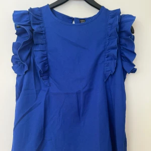blå topp med volang - blå topp med volanger från shein i storlek s, använd bara förra sommaren några gånger, säljer den nu då den inte kommer till användning. inga tecken på användning. skriv för fler bilder, köparen står för frakten