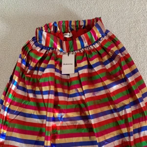 Modström PernilleMD lång kjol med glitter ränder - En super-kalas-festlig kjol från Modström i vackra glittriga ränder. Lång kjol som går ner till fötterna med mycket volym. Vem vill inte rocka denna färgpaletten med glitter? Storlek XS och generös stretch i midjan. Ordinariepris 1200kr.