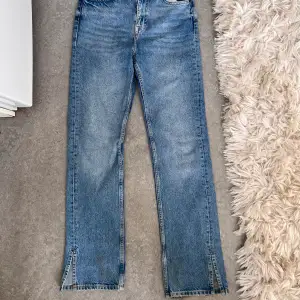 Högmidjade jeans med raka ben med slits nedtill. Inte så mycket stretch i dem 
