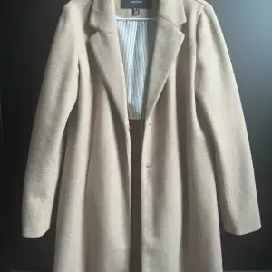 Snygg ofodrad kappa från Vero Moda i storlek medium. Färgen är brunbeige. På mig som är 160cm så ner den till halva låren ungefär. 