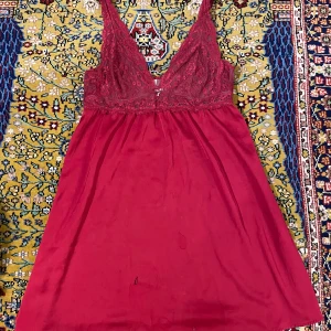 Nattlinne - Superfint rött nattlinne med spets med justerbara axelband. Storlek L. Köptes secondhand men har inte använts av mig pga fel storlek. Den har några små fläckar och hål, syns på sista bilden, därav priset!