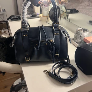 Jättesnygg väska  - Jättesnygg väska i nyskick, aldrig använd. Den har t.o.m. kvar plastet som man kan se på bilen. Det medföljer ett band till. 