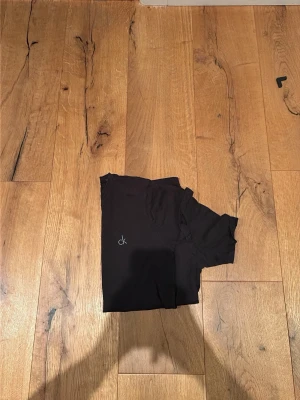 t-shirts från Calvin Klein & Gant 5st - Två stilrena svarta t-shirts, en från Calvin Klein med diskret 'ck'-logga på bröstet och en från Gant med klassisk logga. Båda har rund hals och korta ärmar, perfekta till jeans eller shorts. Materialet känns mjukt och skönt mot huden.