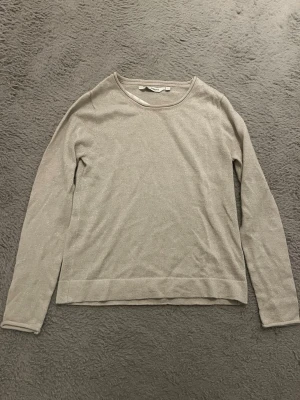 Beige glittrig stickad tröja från KappAhl Stockholmsstil  - Säljer en enkel och stilren beige stickad tröja från KappAhl i storlek XS. Tröjan har rund halsringning, långa ärmar och en glittrig finish i materialet. Perfekt för dig som gillar en clean och klassisk look. Jag tror kanske den är lite urtvättad. 