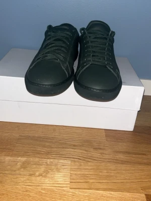 Mörkgröna sneakers från Oliver Cabell - Stilrena mörkgröna sneakers från Oliver Cabell i lågt, klassiskt snitt. Skorna är tillverkade i slätt läder med matchande gröna skosnören och svart sula. Perfekta för dig som gillar minimalistisk och clean stil.