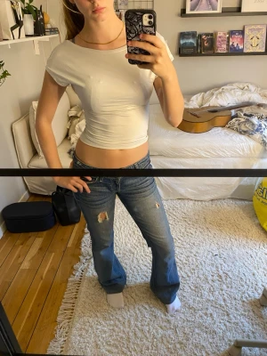 Vit croppad t-shirt - Säljer en vit croppad t-shirt med rund hals och korta ärmar.  Toppen är tight i passformen och har en öppen rygg. Materialet känns mjukt och stretchigt, troligtvis bomull eller en bomullsblandning.