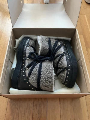 INUIKII Curly rock - Säljer ett par supersnygga skor från INUIKII med svarta detaljer och snörning. Skorna har fluffig in- och utsida, robust sula, dekorativa nitar. Perfekta för kalla dagar och ger en cool vinterlook😇💖De är använda men har inga defekter som påverkar användning annars se bilder för skick💖