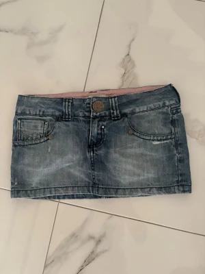 Blå jeanskjol! - Snygg blå jeanskjol ifrån sicko i storlek S/M. I modellen är den lågmidjad och ganska kort. Super fina fickor och små rosa detaljer på kjolen!💗💗